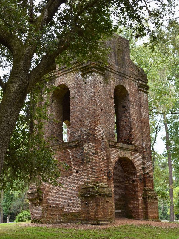 A brick bell tower stands among the trees, now empty and in ruins at Colonial Dorchester