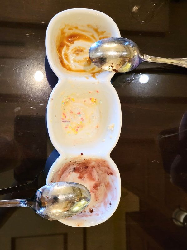 An empty dish with 2 spoons and the remains of ice cream