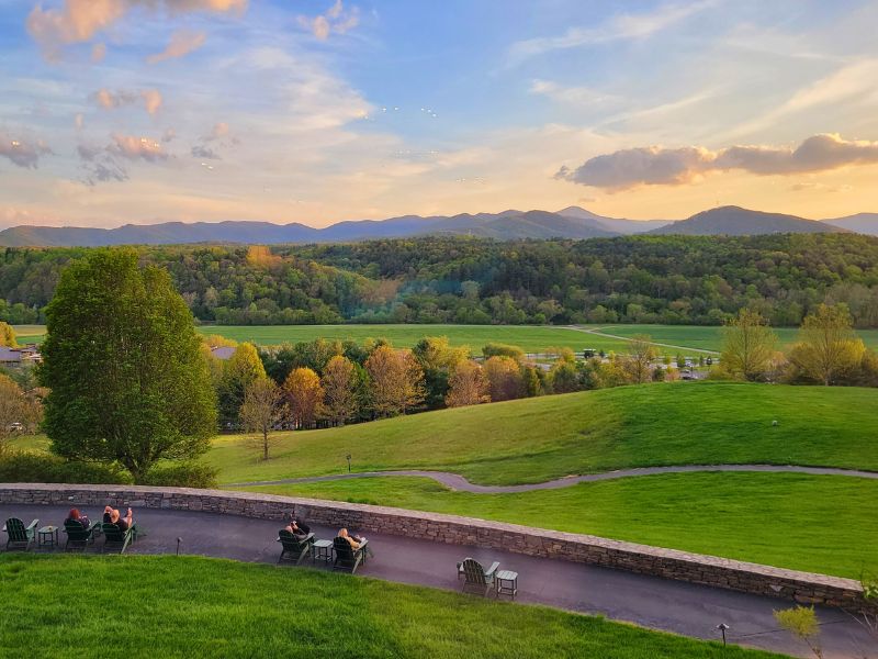 Soft glow of sunset over green hills and forest from the back patio of The Inn at Biltmore